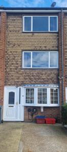 a brick building with a white door and windows at Cozy flat & Lovely garden, High Speed WiFi in Cranford