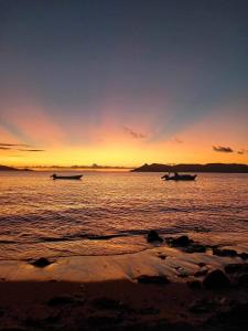 - deux bateaux dans l'eau au coucher du soleil sur la plage dans l'établissement Yawekata Eco Still BlueWater Resort, à Ngunu 4 autres photos
