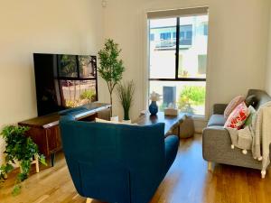 un soggiorno con un divano blu e una TV di Luxurious Suite a Woodville South