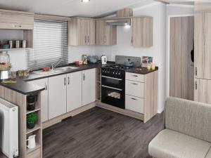 eine Küche mit weißen Schränken, einem Backofen und einer Spüle in der Unterkunft Thurston Essential Clover Caravan 1 in Dunbar