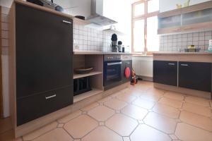 cocina con armarios negros y suelo de baldosa blanca en Fewo Leonhardt, en Görlitz