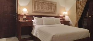 una habitación de hotel con una cama y dos lámparas en las mesas en Villa Gadja Bali, en Jimbaran 59 fotos más