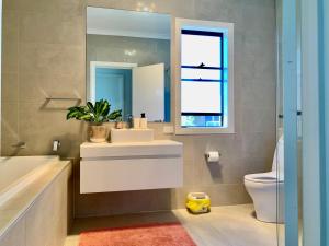 un bagno con lavandino, WC e specchio di Stellar Suite a Woodville South Altre 8 foto