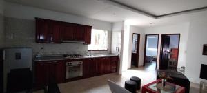 a kitchen with wooden cabinets and a living room at Apartamento Vacacional centro San Gil in San Gil
