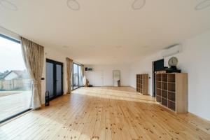 an empty room with a wooden floor and large windows at SunMoon Kosmaj kućice i prostor za događaje in Sopot