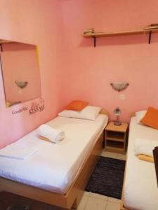 two beds in a room with pink walls at Apartment DARINA in Nečujam