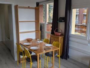une table en bois avec des chaises jaunes et une table avec des verres dans l'établissement Maxi Studio 5 pers. avec balcon, WIFI, pieds des pistes, calme, proche commerces et sports - FR-1-262-75, à Forest des Baniols 6 autres photos