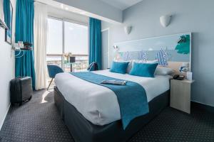 a hotel room with a large bed with blue accents at Best Western Hôtel Royan Océan in Royan