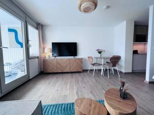 un salon avec une télévision et une table dans l'établissement Apartment mit Wintergarten & Grüner Aussicht im Schwarzwald, à Löffingen