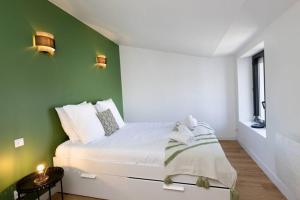 Un dormitorio con una cama con una pared verde. en Le Loft Caché, en Carcassonne