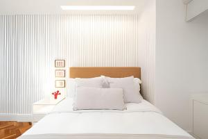 a white bedroom with a bed with white pillows at Prédio - El Paso - Acomodações estilosas do Leblon - por Casapē in Rio de Janeiro