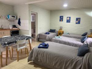 ein Zimmer mit drei Betten und einem Tisch und einer Küche in der Unterkunft Las Castañas in General Acha