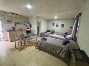 ein Zimmer mit zwei Betten und einem Tisch und einer Küche in der Unterkunft Las Castañas in General Acha