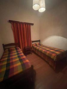 a room with two beds in a room with a curtain at Casa en medio de las montañas in Potrerillos +9 photos