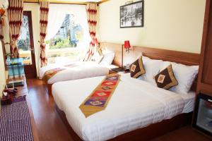 een hotelkamer met 2 bedden en een raam bij Sapa Dragon Hotel in Sa Pa