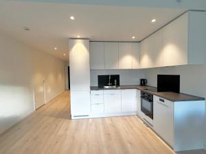 a kitchen with white cabinets and a wooden floor at Modern apartment with two bedrooms in Moelv