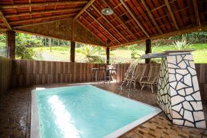 a swimming pool under a pavilion with a table at Pousada Casa da Moeda in Brumadinho