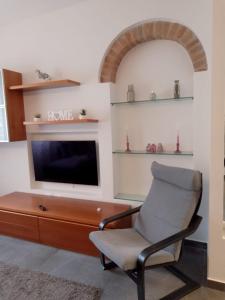 a living room with a chair and a television at Appartamento Loreto-Fiera in Cremona