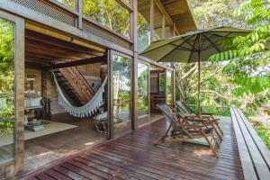 an open deck with a hammock and an umbrella at A Casinha da Floresta in Gamboa +6 photos