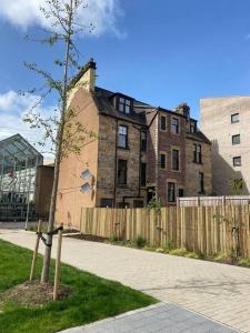 a tree in front of a building with a fence at 3 Smithhills Paisley central spacious sleeps 4 in Paisley