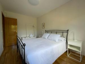 a bedroom with a large bed with white sheets at Los Balcones de Vega in Vega de Espinareda
