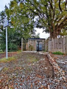 ein Haus mit einem Baum und einem Holzzaun in der Unterkunft Au Poème du Chêne, Logement indépendant, Calme, Parking gratuit in Basse-Goulaine