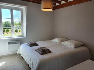 a bedroom with a white bed with towels on it at La Bergerie in Saigneville