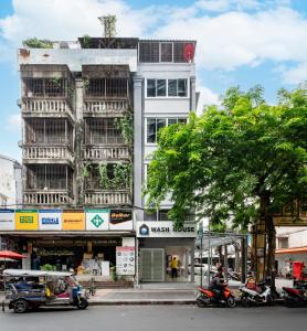 a tall white building on a city street with motorcycles at Wash House Chatuchak in Bangkok