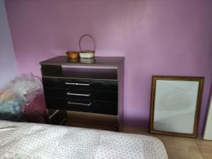 a bedroom with a dresser with a mirror and purple walls at Casa mobiliada privativa in Caiçara