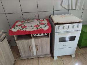 a kitchen with a stove and a counter with a table at Casa mobiliada privativa in Caiçara