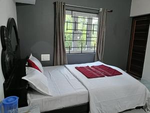 a bedroom with a bed with red pillows and a window at Coorg wildstone Homestay in Madikeri