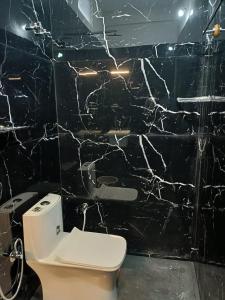 a bathroom with a toilet and a black marble wall at Coorg wildstone Homestay in Madikeri