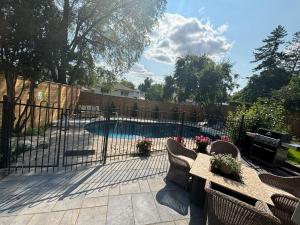 a fence with chairs and a table and a pool at Bright & Cozy 4BR Home for Your Family Stay With Optional Pool Access in Mississauga
