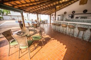a patio with chairs and tables and a bar at Ville Hotel Gramadão in Votuporanga
