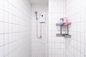 a white tiled bathroom with a shower with a shower head at Wash House Chatuchak in Bangkok +46 photos