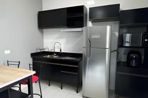a kitchen with a stainless steel refrigerator and a table at Condomínio Canto da Ema in São Paulo