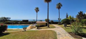 a resort with a swimming pool and palm trees at Apartamento en zona Cabopino in Marbella