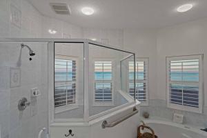 a bathroom with a shower and a tub and windows at Beachfront Vilano Retreat in Saint Augustine +40 photos