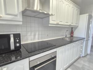 a white kitchen with a sink and a microwave at Apartamento en primera línea de playa, Mi Capricho in Sitio de Calahonda