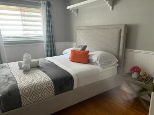 a bedroom with a bed with white sheets and orange pillows at Bright & Cozy 4BR Home for Your Family Stay With Optional Pool Access in Mississauga +37 photos