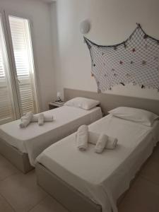 2 camas en un dormitorio con sábanas y almohadas blancas en Villa Luxury fronte mare, en San Vito lo Capo