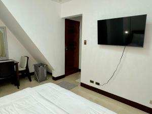 a bedroom with a bed and a flat screen tv on a wall at Serena Rooms in El Nido