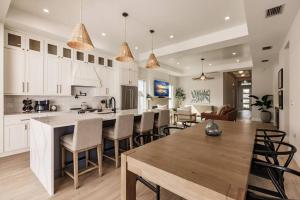 ネープルズにあるNaples Paradise Cove Luxury Beach Homeのキッチン、リビングルーム(白いキャビネット、テーブル付)