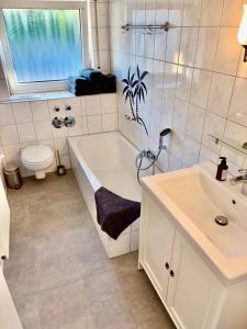 a bathroom with a tub and a sink and a toilet at RelaxStay - Balkon - Smart-TV - WIFI in Dielheim