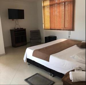 a bedroom with a bed and a television and a chair at Hotel la quinta campestre in Villavicencio