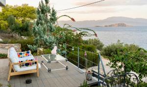 balcón con mesa de cristal y vistas al agua en Deck House, en Pefkali