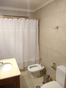 ein Badezimmer mit Toilette, Waschbecken und Duschvorhang in der Unterkunft Casa para 16 personas in Carilo