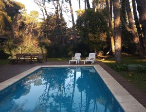 einen Pool mit 2 Stühlen und einem Picknicktisch in der Unterkunft Casa para 16 personas in Carilo + 10 Fotos