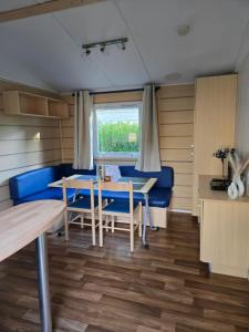 a dining room with a blue couch and a table at Mobil-home Beau Rivage in Gunsbach +10 photos