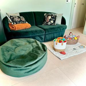 a living room with a green couch and baskets of toys at White Oaks Sussex in Twineham